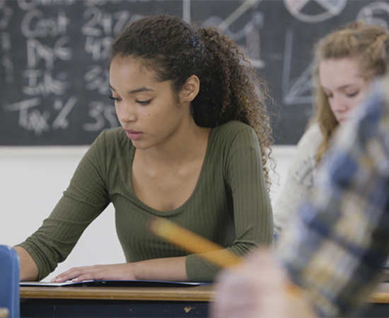 A teen in a classroom, concentrating on a test.